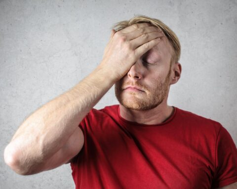 a man in red shirt covering his face