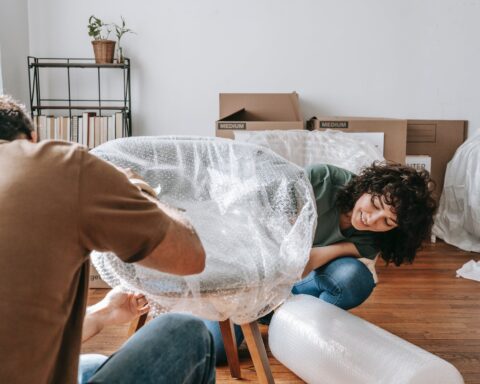 couple wrapping a chair with plastic