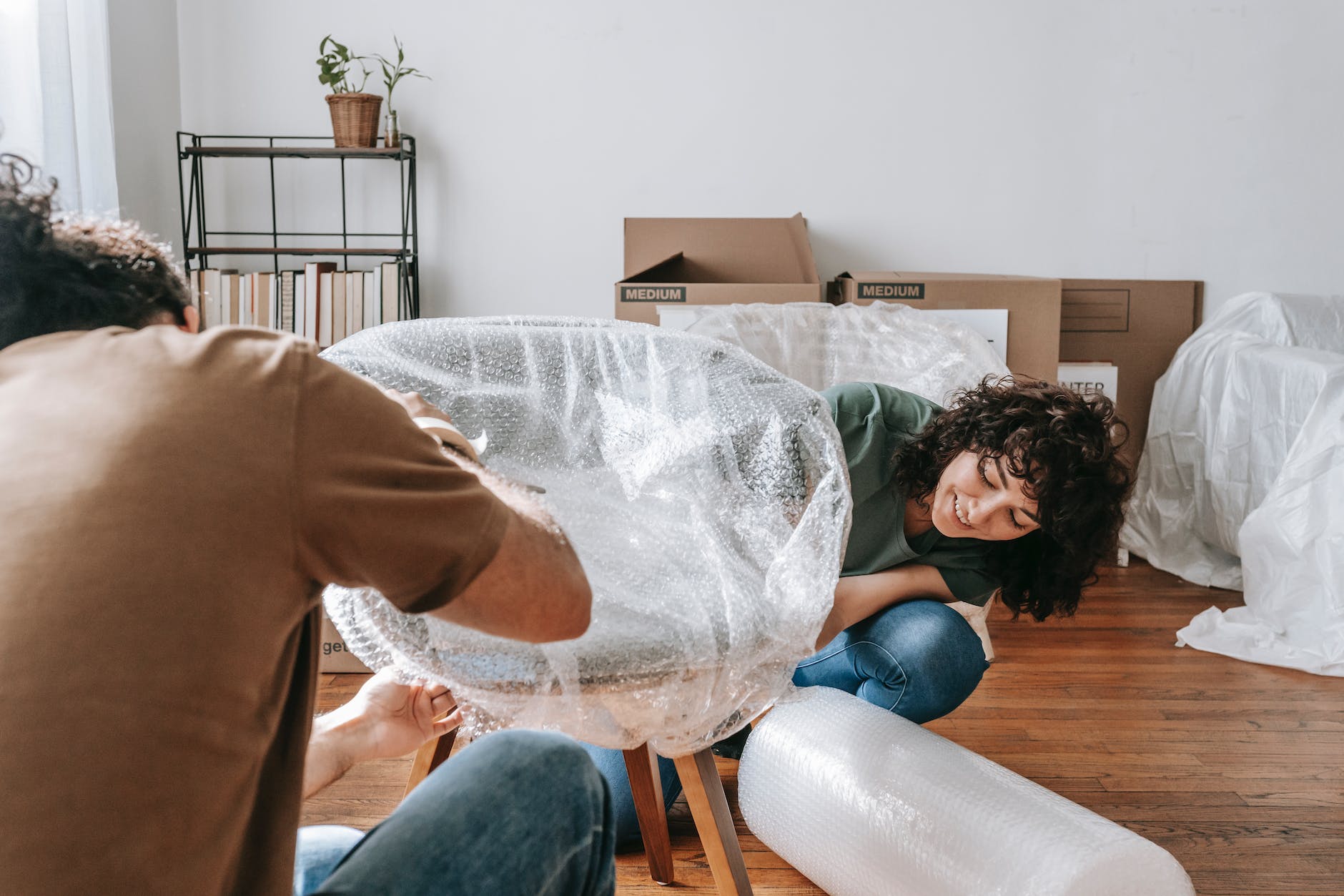 couple wrapping a chair with plastic